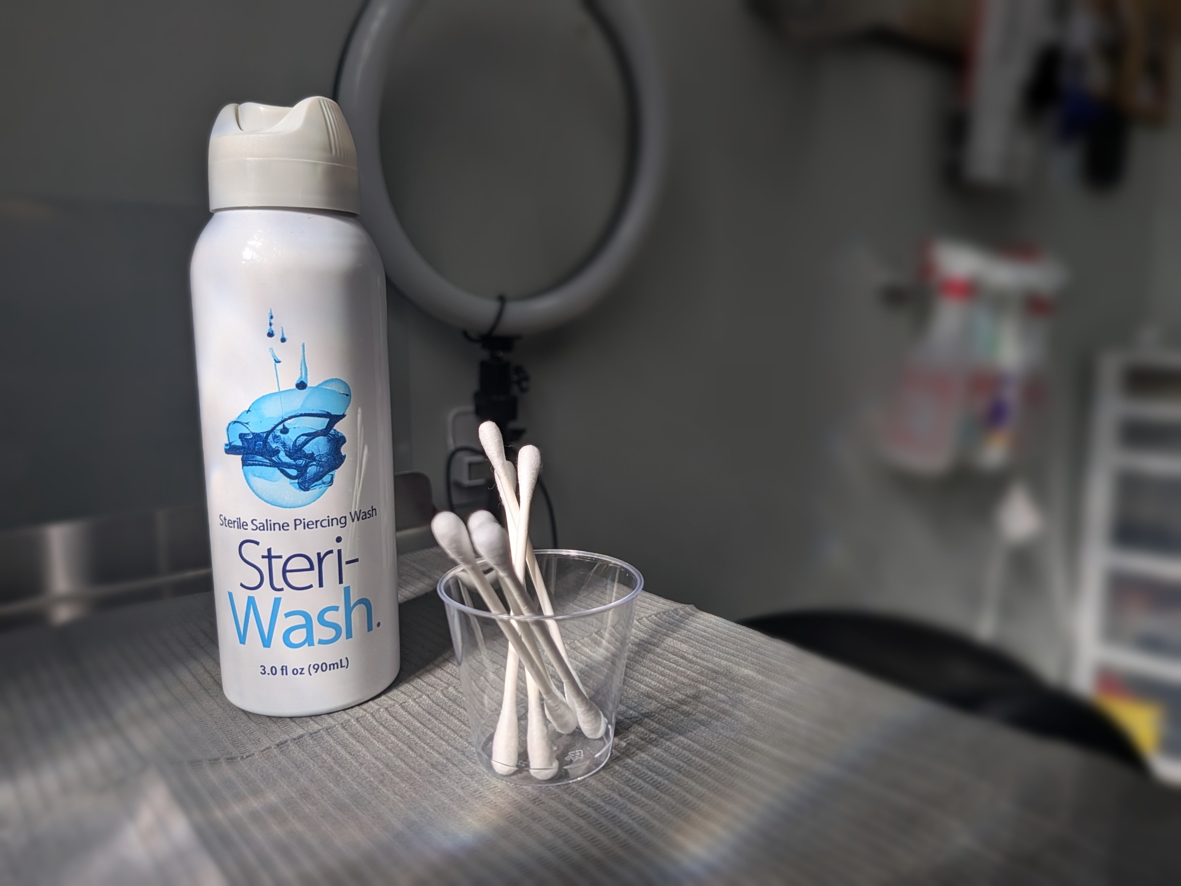 Sterile saline solution and Q-tips for piercing aftercare setup in natural sunlight in London, Ontario