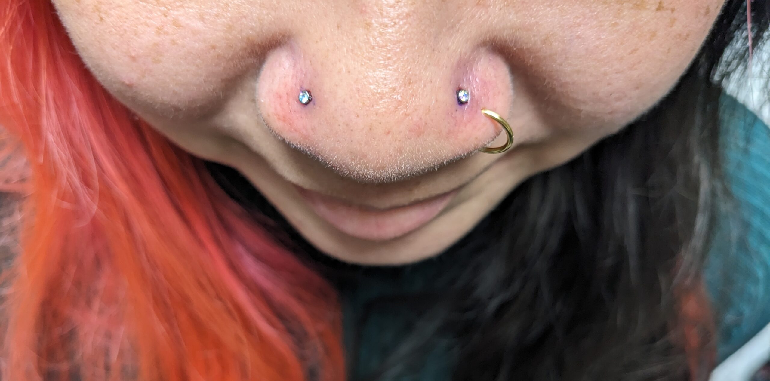 Close-up of double nose piercings with one stud on each nostril.